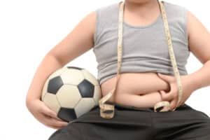 Obese fat boy holding football isolated over white diet to lose weight and healthy concept