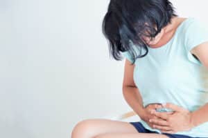 Closeup ill young woman on sofa. concept suffering from abdominal pain